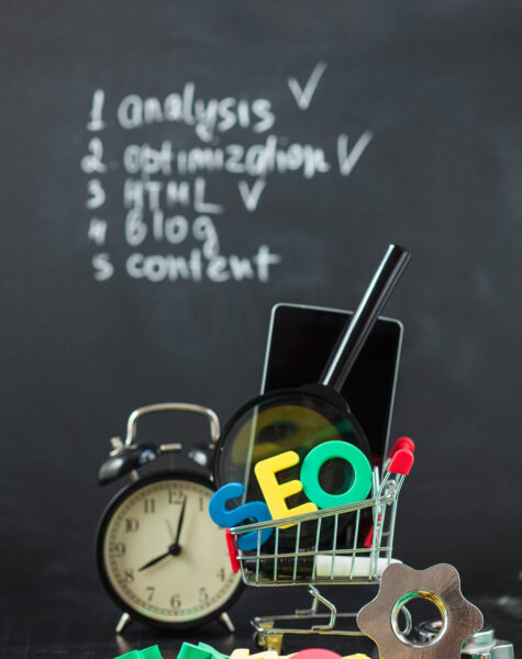 SEO Search engine optimization concept Colored letters of SEO with clock, magnifying , smartphone, gears in a basket on a black background Closeup